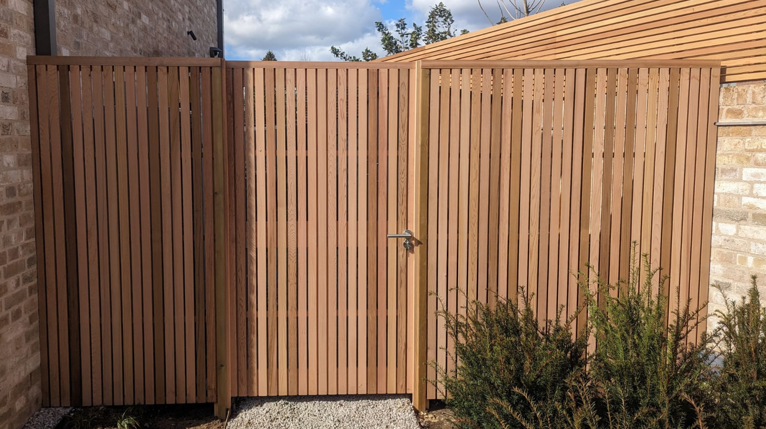 Bespoke vertical slatted fence and gate with matching horizontal slatted panels around the perimeter
