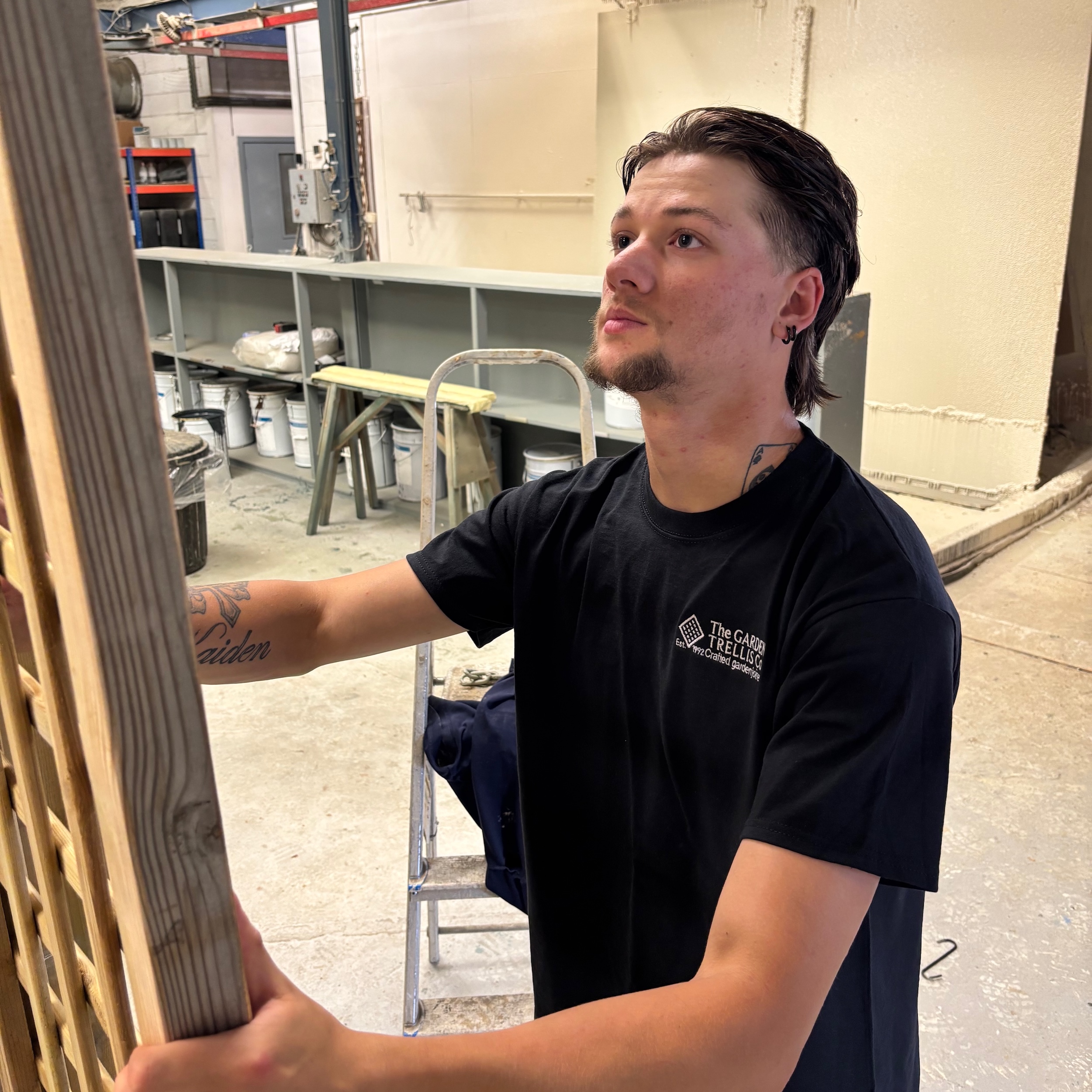 A man in a black t-shirt moving trellis, ready for painting