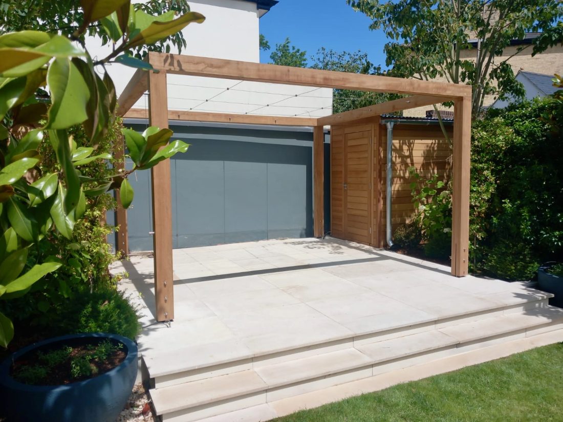 A bespoke pergola (in Iroko) with a bespoke shed on either side