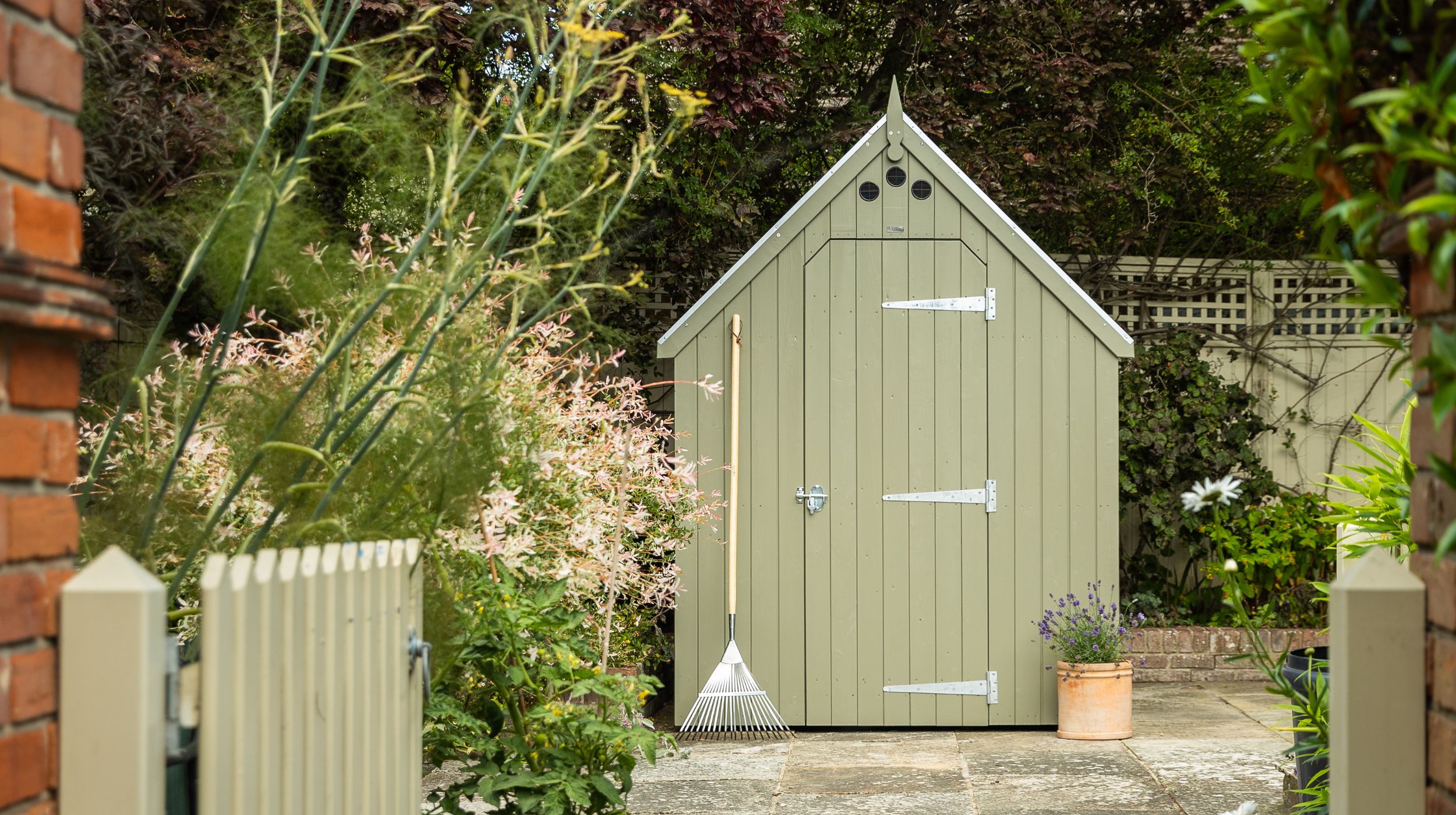 RHS Large Garden Shed in Manhattan Grey with a matching picket gate in a pretty summer garden