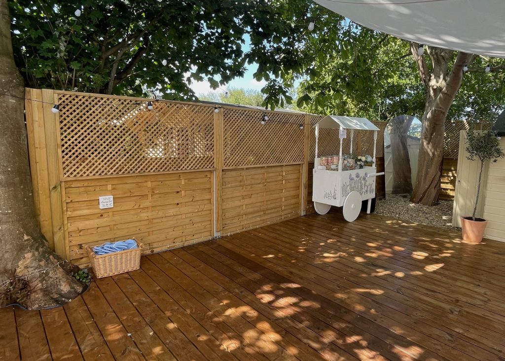 Solid Fence Panels with Diagonal Privacy Trellis surrounding a decking area which is set up for dancing at a home wedding