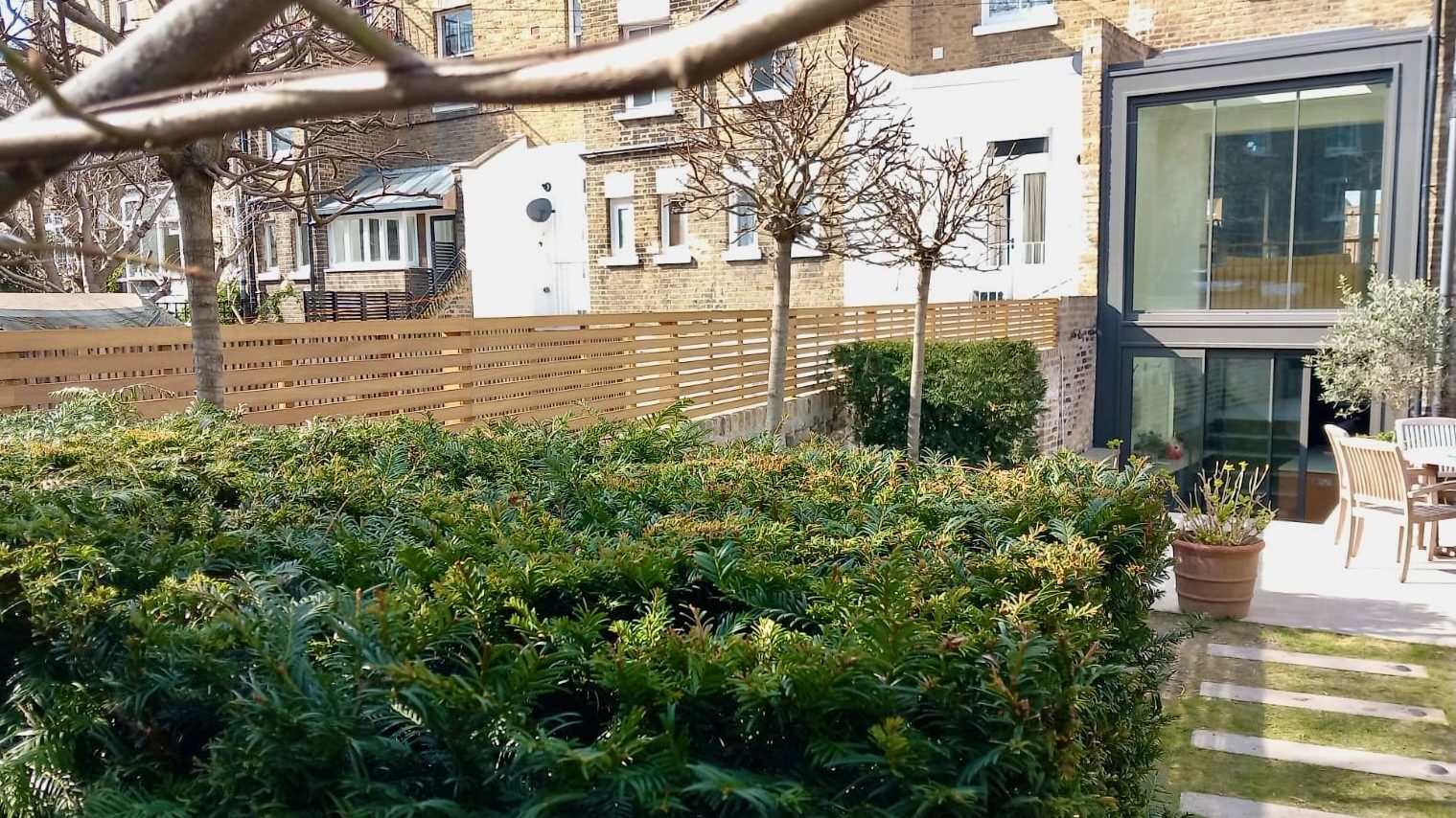 Bespoke Wide Slatted Panels in Iroko on top of a brick wall