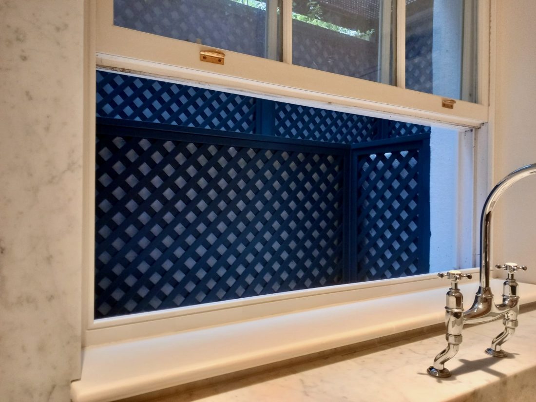 Bespoke diagonal trellis, with a 38mm gap, thermowood painted in bespoke colour Mylands Murmurations making a basement light well more interesting.