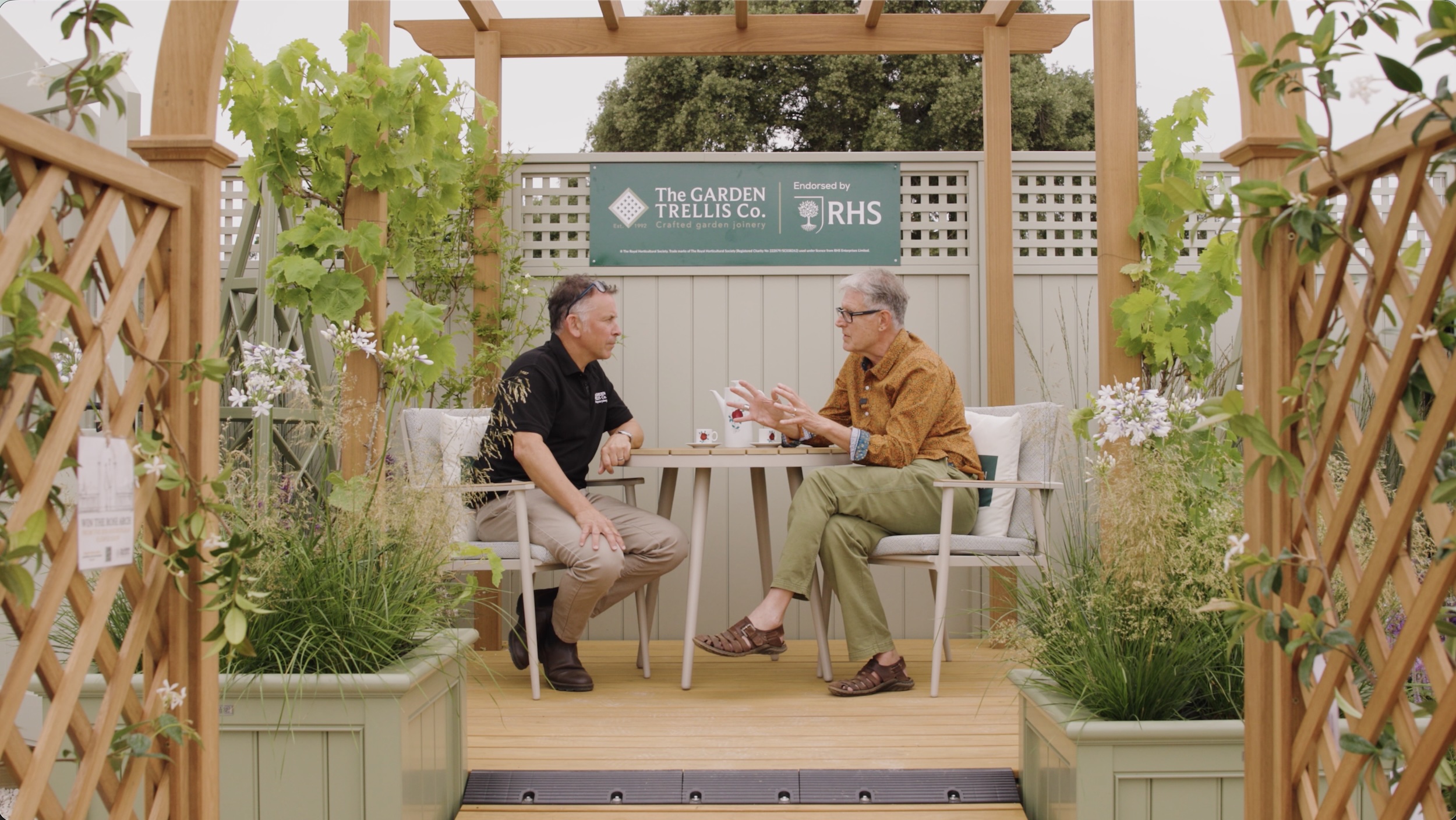 Paul Baines and Julian Furness sitting and talking at the Garden Trellis Co stand at RHS Sandringham Flower Show.