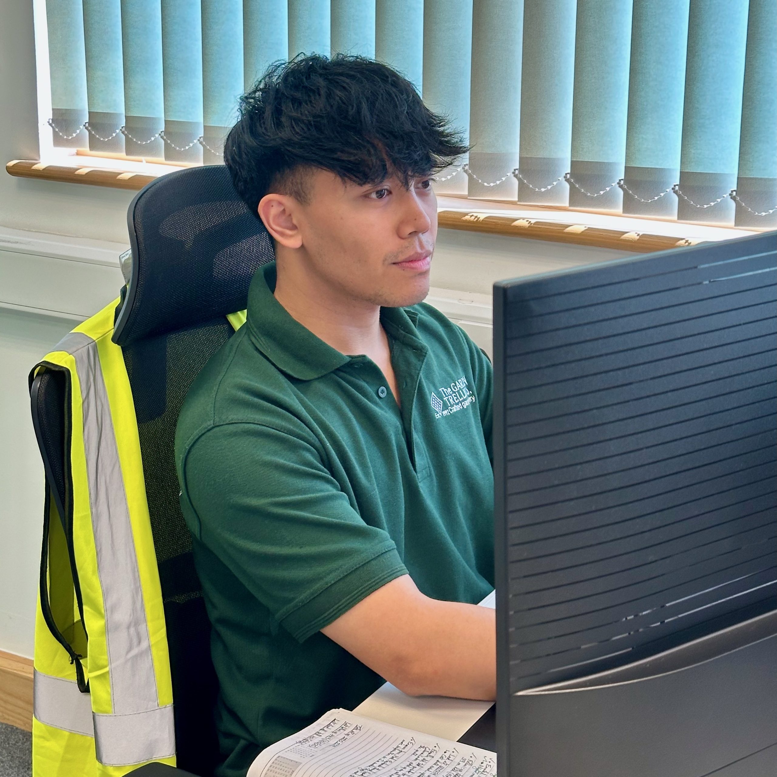 Picture of a man wearing a green Garden Trellis Co t-shirt, working at a computer