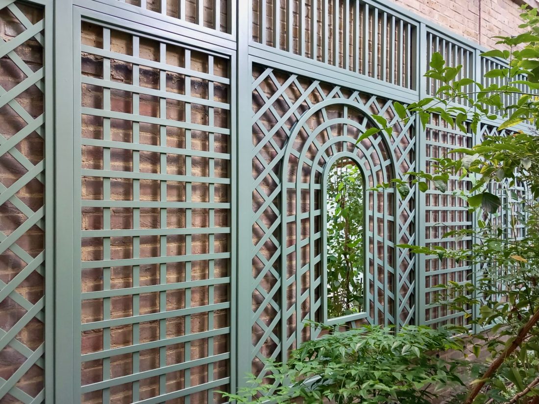 A photo of decorative trellis fixed to a large brick wall with ladders, mirrors and Trompe l'œil details painted in Greenwich Green